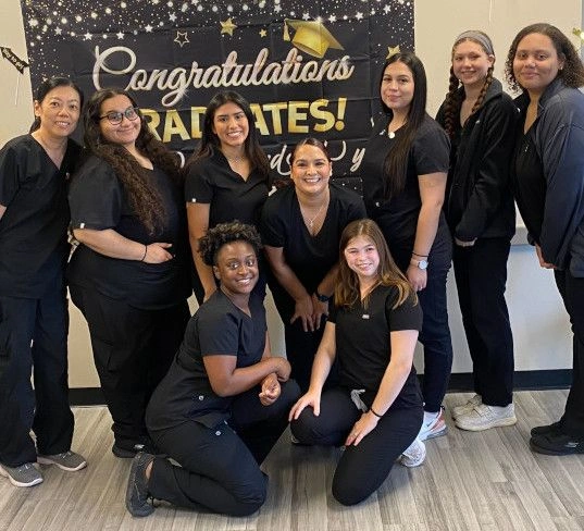 graduates standing in front of congratulatory banner