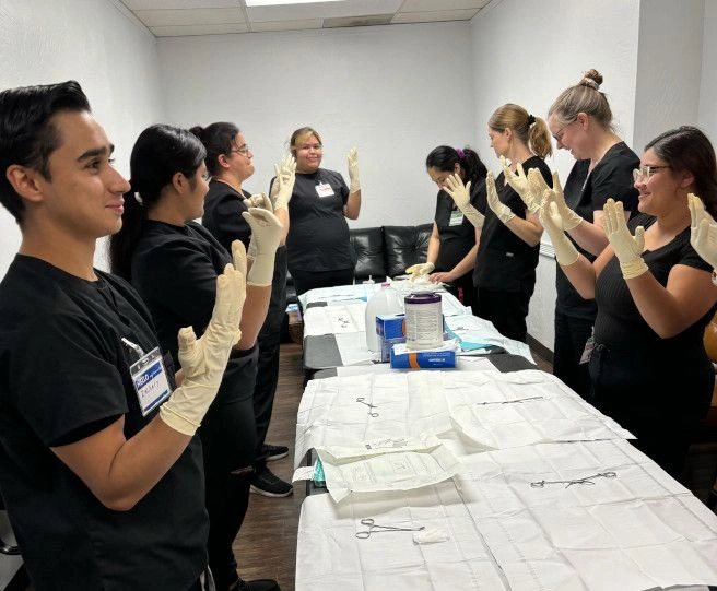 students taking a group photo with hands raised with gloves on students taking a group photo with hands raised with gloves on